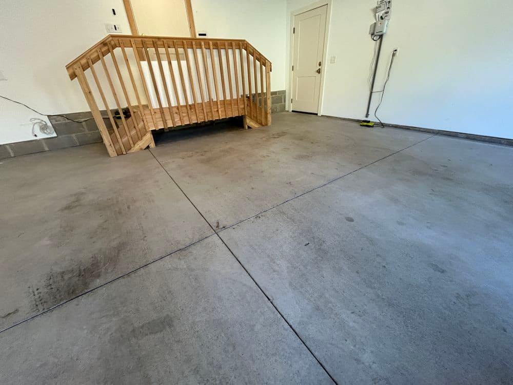 Wooden ramp leads to a garage with clean concrete floor and door, promoting accessibility.