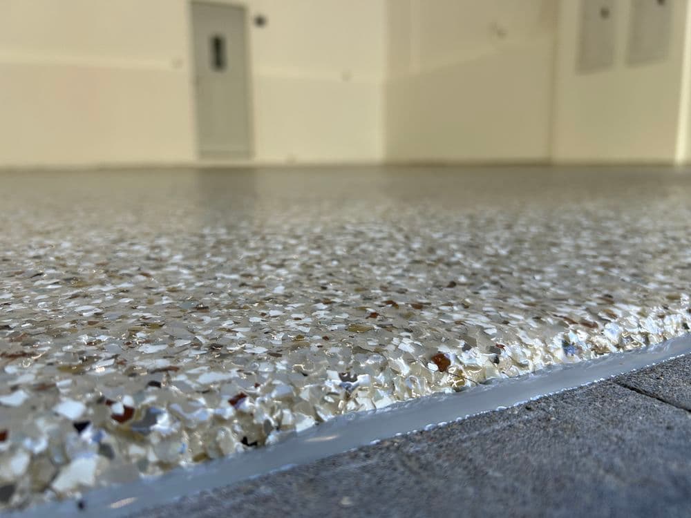 Close-up of a smooth, shiny epoxy floor with decorative flakes in a spacious interior setting.