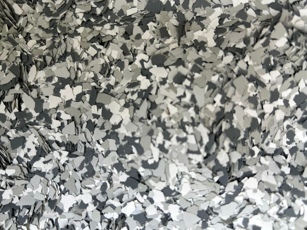 Gray and white paint chips scattered on a surface, ideal for texture and color analysis.
