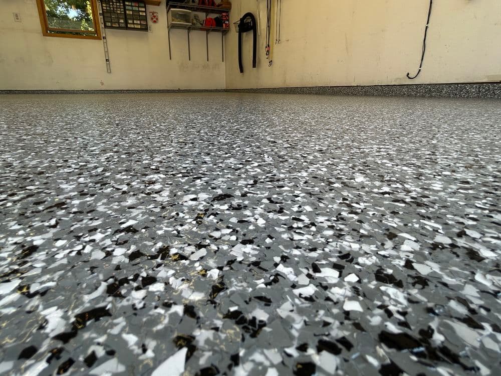 Close-up of a freshly coated gray garage floor with black and white specks.