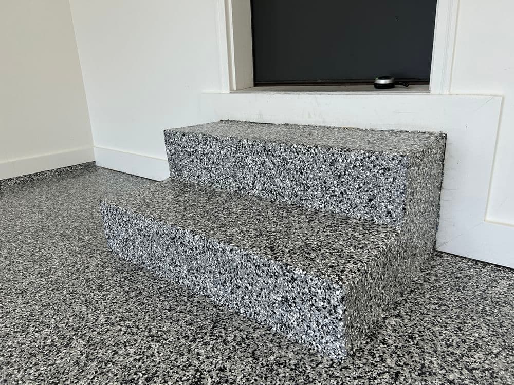 Granite steps leading to a dark entryway with a textured, speckled floor.