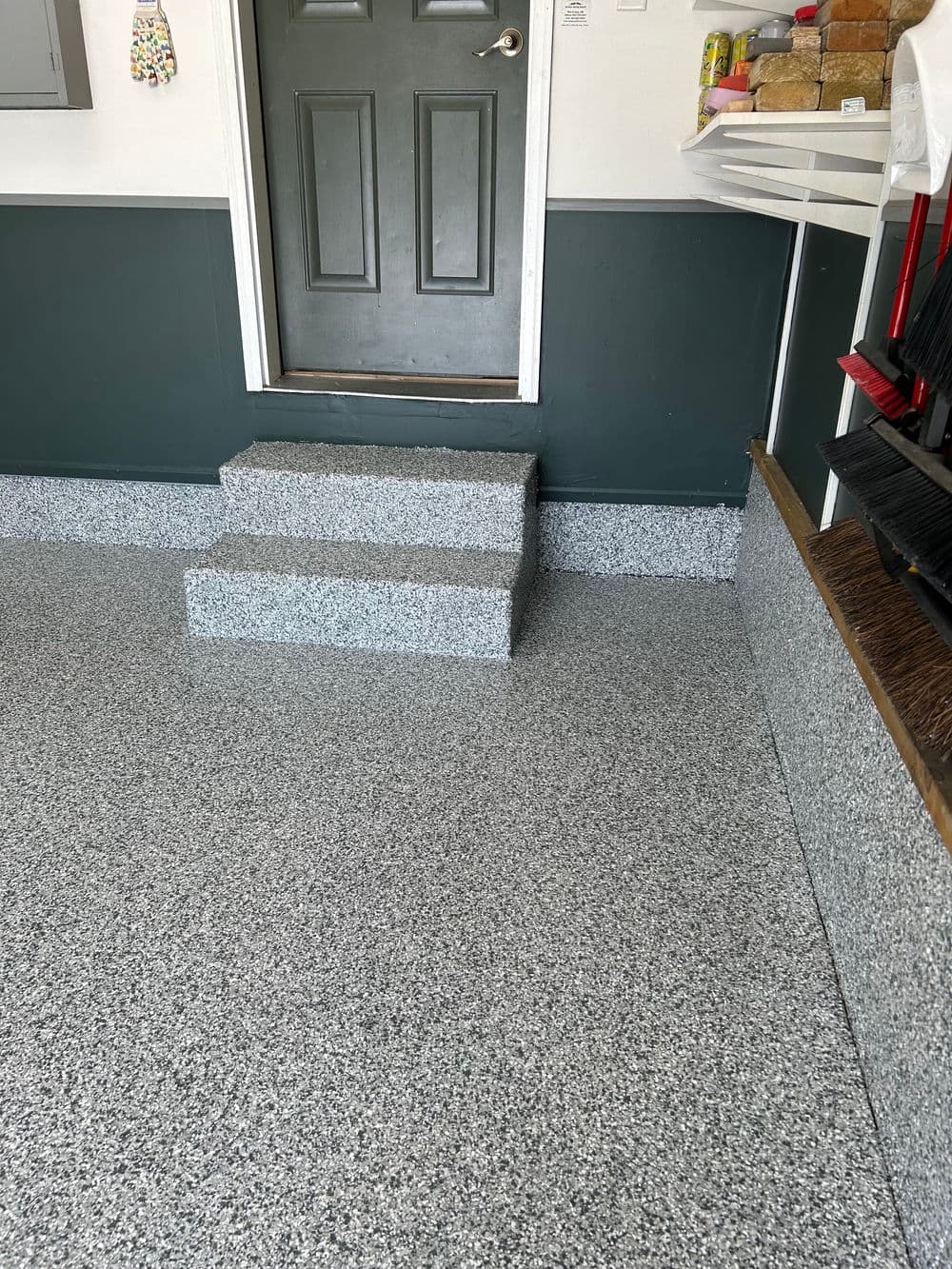 Garage interior featuring a three-step entrance and decorative epoxy flooring.