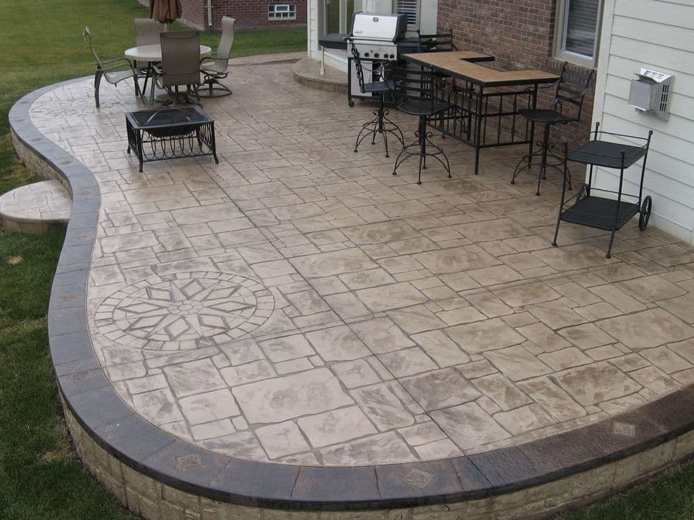 Stylish outdoor patio with stamped concrete design, dining area, and grill setup.